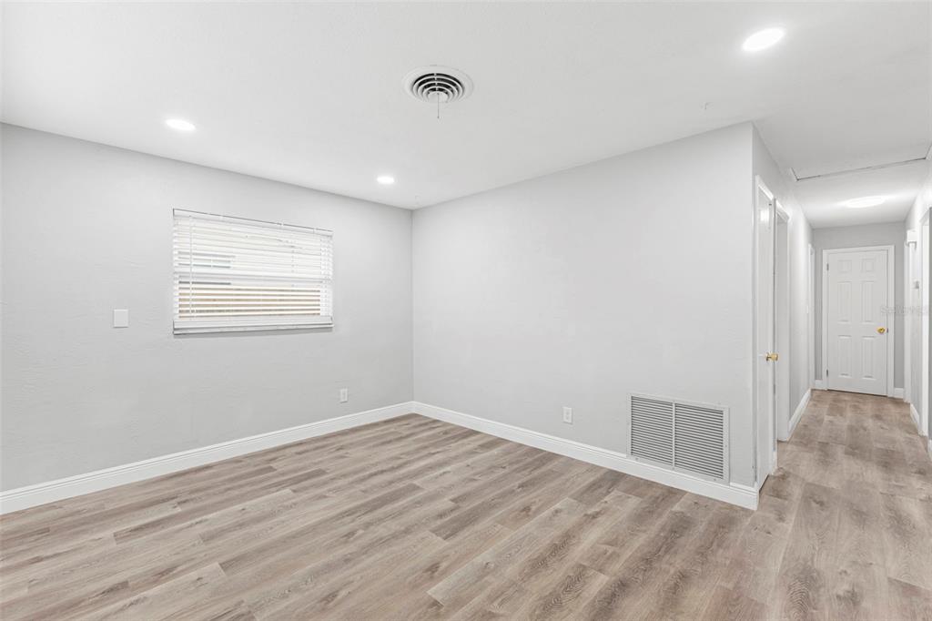 An empty room with light gray walls, wood-look flooring, a window, and a white door — 2443 26TH AVENUE S, ST PETERSBURG, FL