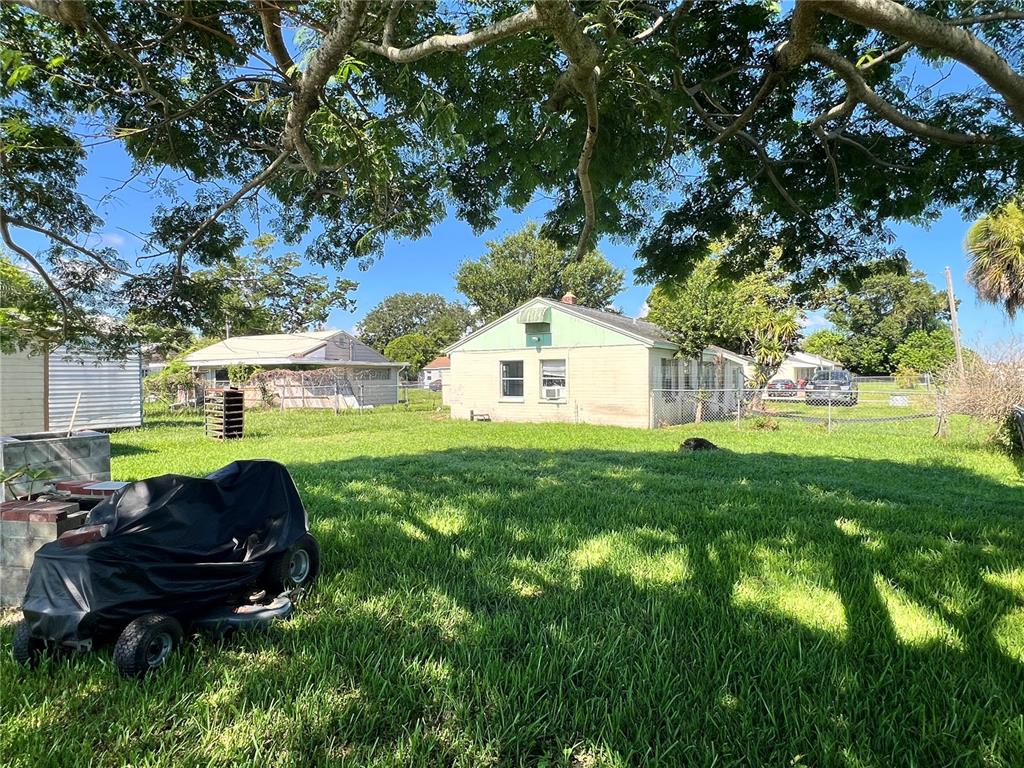 A backyard view features a lawn, a covered riding mower, and two small residential houses — 104 GRACE AVENUE, COCOA, FL