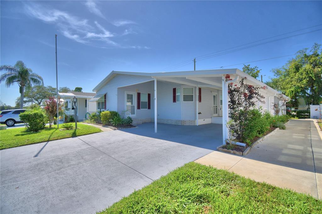 A light-gray manufactured home with a carport, driveway, and small front garden — 6086 SOUTHERN OAKS DRIVE, WINTER HAVEN, FL