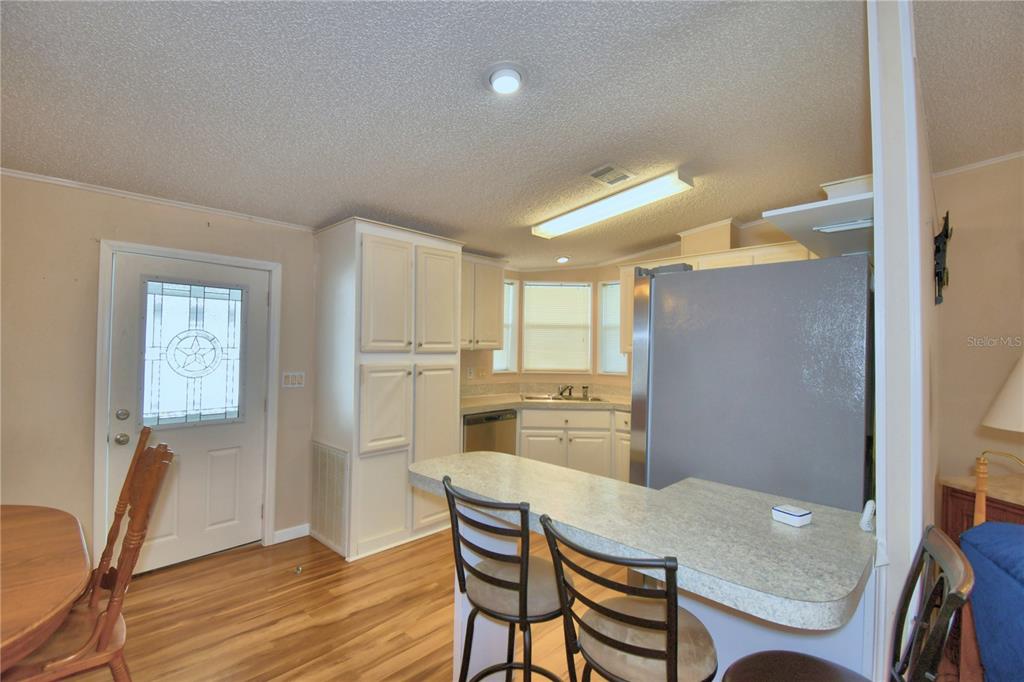 A kitchen features white cabinets, stainless steel appliances, a corner sink, and wood-look flooring — 6086 SOUTHERN OAKS DRIVE, WINTER HAVEN, FL