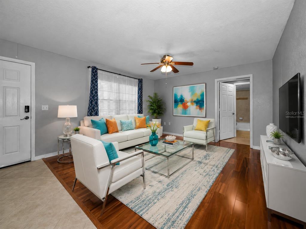 A living room with white furniture, a glass coffee table, and wood flooring — 6100 GULFPORT BOULEVARD S UNIT 405, GULFPORT, FL