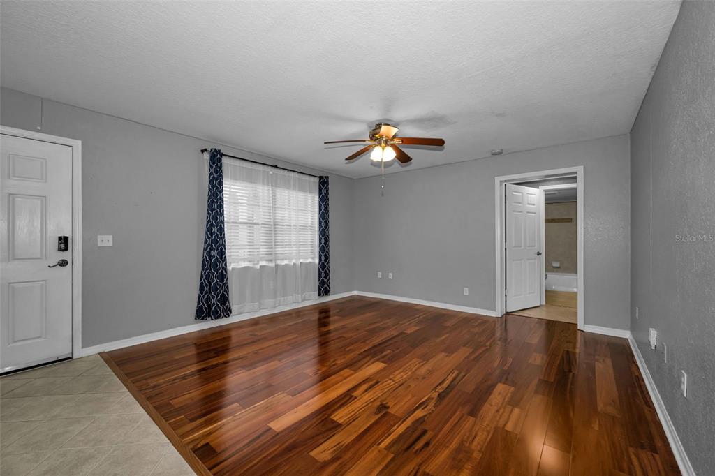 An empty living room features gray walls, dark hardwood flooring, and a ceiling fan — 6100 GULFPORT BOULEVARD S UNIT 405, GULFPORT, FL