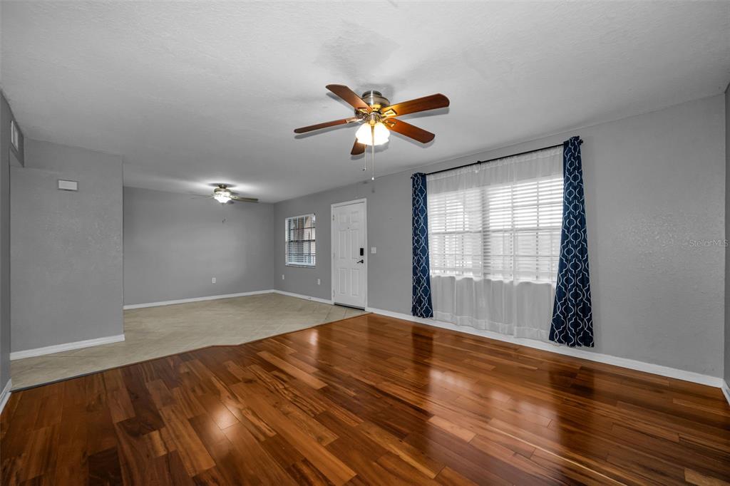 A living room with hardwood floors, gray walls, a ceiling fan, and a large window — 6100 GULFPORT BOULEVARD S UNIT 405, GULFPORT, FL
