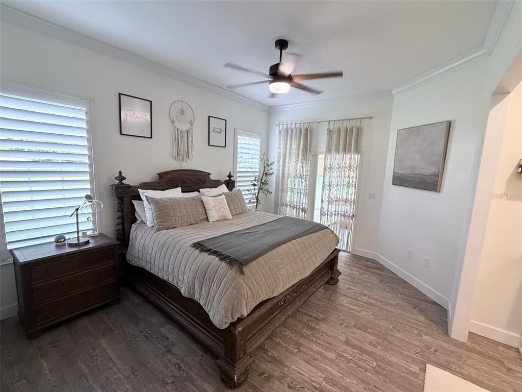 A bedroom features a wooden bed frame, a ceiling fan, and a dresser by a window — 25162 NW 204TH PLACE, HIGH SPRINGS, FL