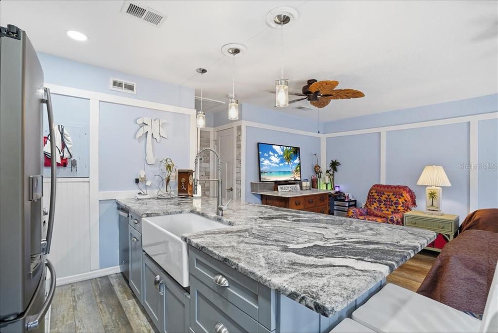 A kitchen island with a farmhouse sink and granite countertop sits in a blue room — 8931 BLIND PASS ROAD UNIT 360, ST PETE BEACH, FL
