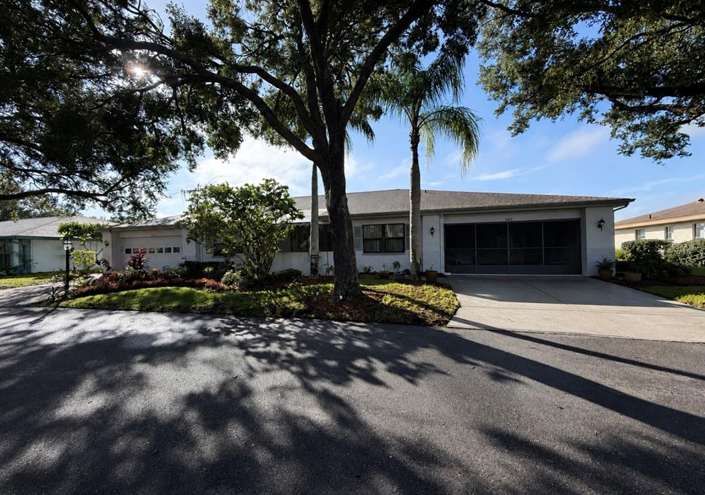 A single-story house with a two-car garage, a palm tree, and mature landscaping — 2417 LOCKSLEY STREET UNIT 229, SUN CITY CENTER, FL