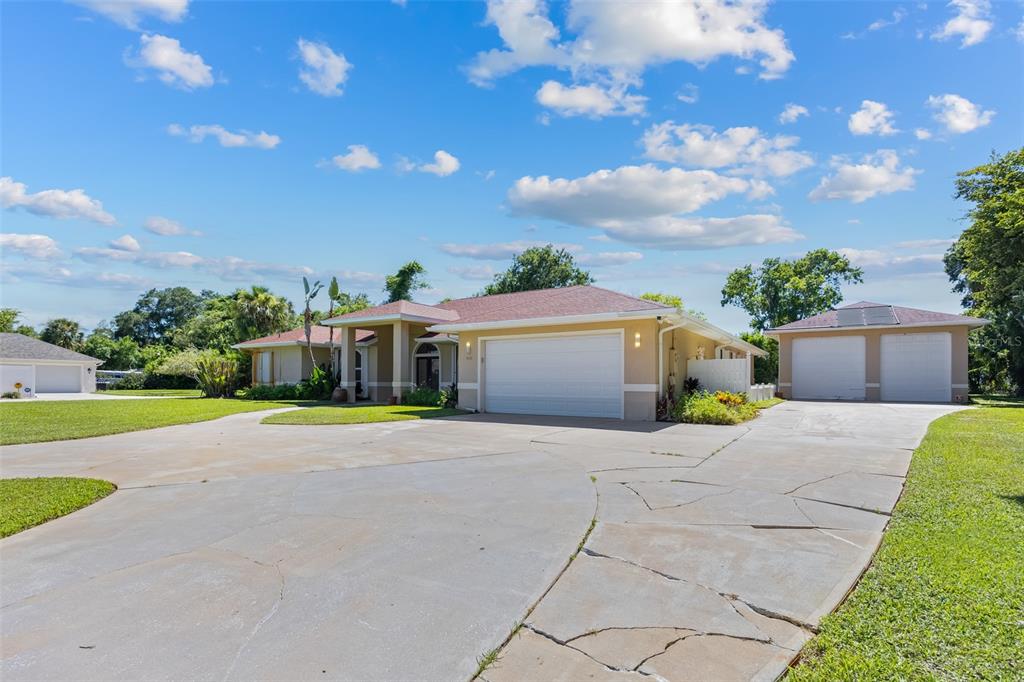 A single-story house with a large concrete driveway and a detached two-car garage — 4135 INDIAN RIVER DRIVE, COCOA, FL
