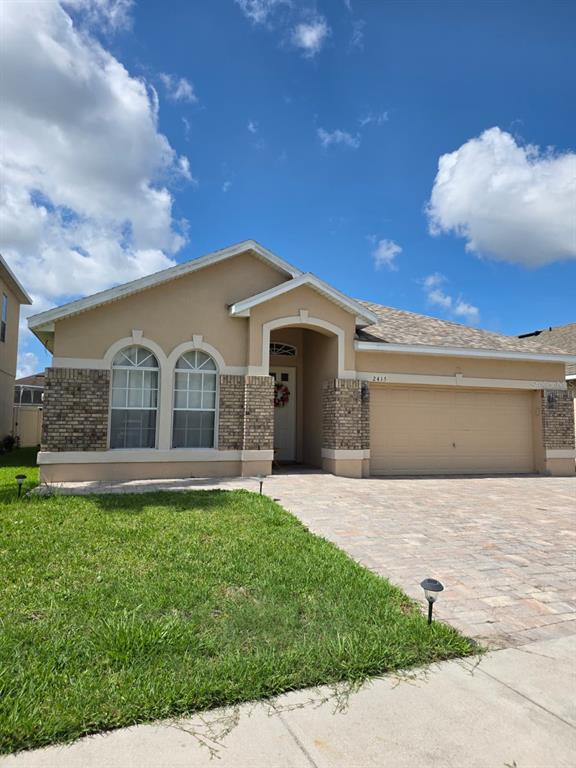 A single-story house with a tan stucco exterior, brick accents, and a paved driveway — 2415 SAND ARBOR CIRCLE, ORLANDO, FL
