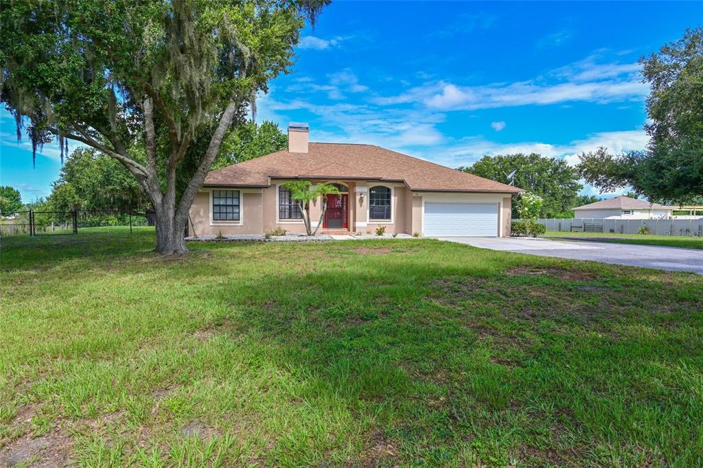 A single-story house with a tan exterior, a two-car garage, and a large front yard — 4415 N RYE ROAD, PARRISH, FL