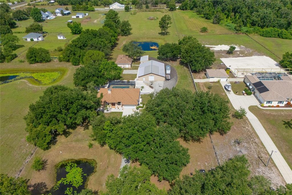 An aerial view shows a house with a pool, a large workshop, and two ponds — 4415 N RYE ROAD, PARRISH, FL