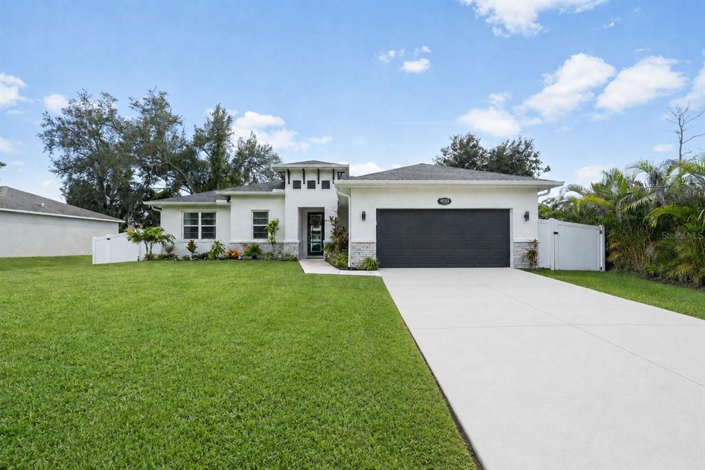 A single-story house with a white stucco exterior, a dark garage door, and a grassy lawn — 4033 UNION LANE, NORTH PORT, FL