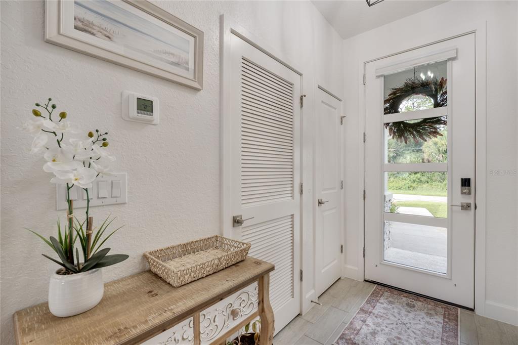 A bright entryway features a white front door, a louvered closet door, and a console table — 4033 UNION LANE, NORTH PORT, FL