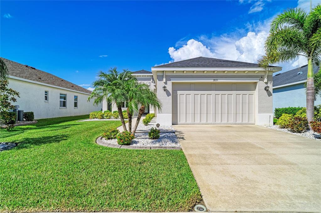 A single-story house with a beige exterior, a two-car garage, and a palm tree — 3835 CREEKSIDE PARK DRIVE, PARRISH, FL