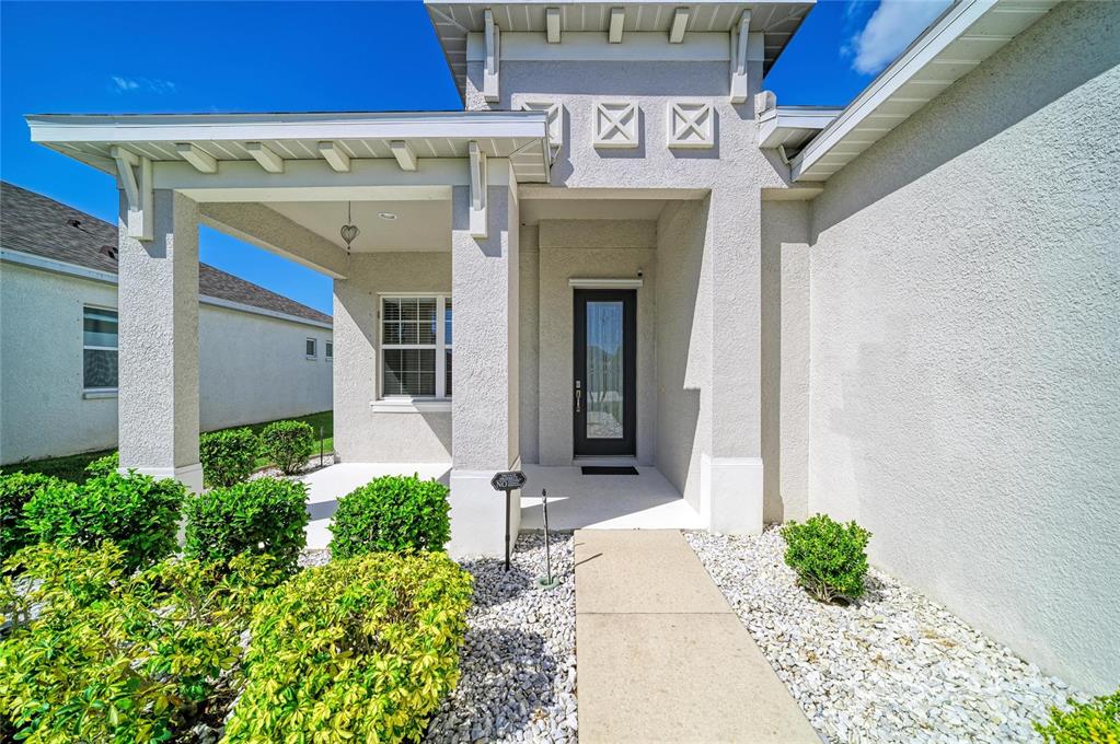 The exterior of a house features a covered entryway, a glass-paneled door, and landscaped bushes — 3835 CREEKSIDE PARK DRIVE, PARRISH, FL