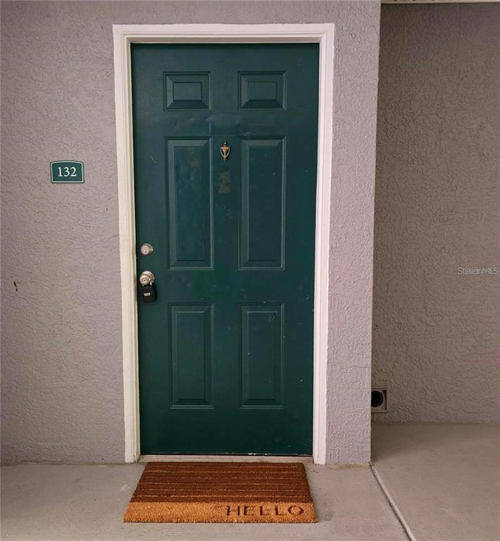 A green front door with a number 132 sign and a hello doormat — 18001 RICHMOND PLACE DRIVE UNIT 132, TAMPA, FL