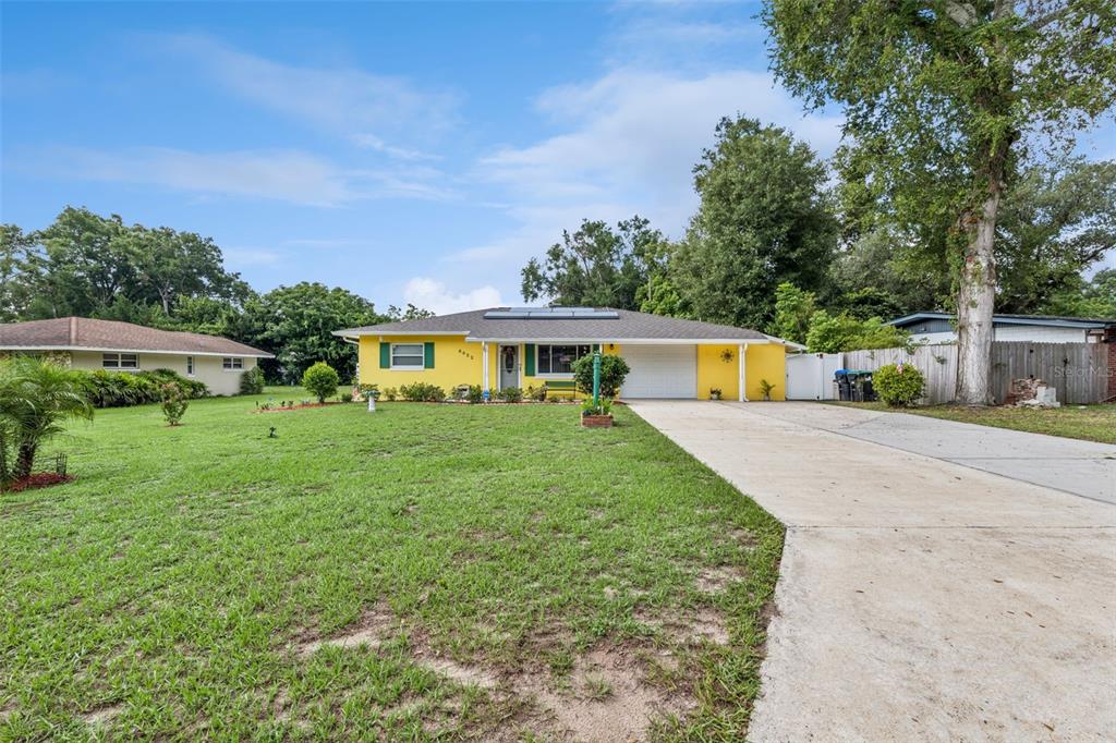A single-story yellow house with a concrete driveway and a large front lawn — 6832 OSWEGO DRIVE, MOUNT DORA, FL