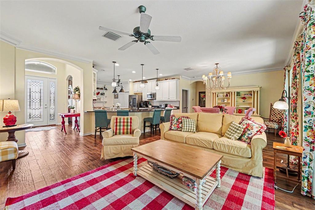 A living room with a plaid rug, yellow sofa, and open kitchen with bar seating — 10202 HYANNISPORT LOOP, SAN ANTONIO, FL