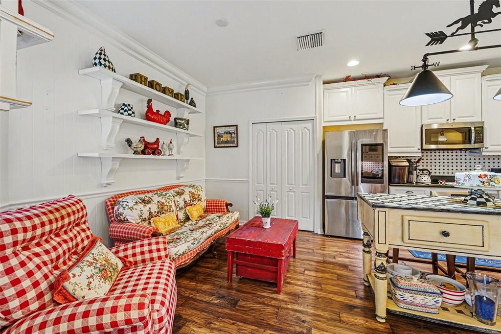 A kitchen and sitting area features white cabinetry, wooden floors, and red-checkered furniture — 10202 HYANNISPORT LOOP, SAN ANTONIO, FL