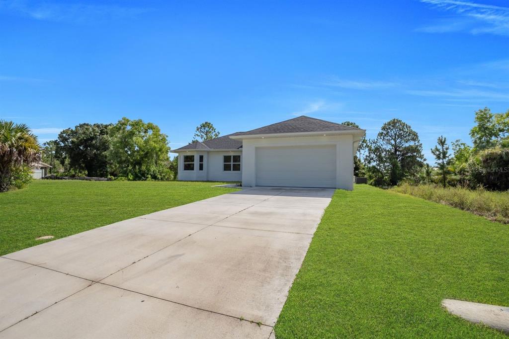 A single-story house with a white exterior, a two-car garage, and a concrete driveway — 523 HARRY THAYER AVENUE S, LEHIGH ACRES, FL