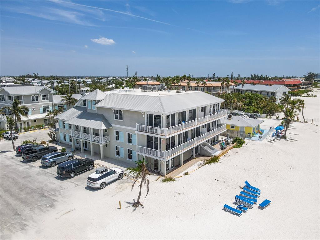 An aerial view shows a multi-story beach house with a parking area and sandy beach — 101 66TH STREET UNIT 6, HOLMES BEACH, FL