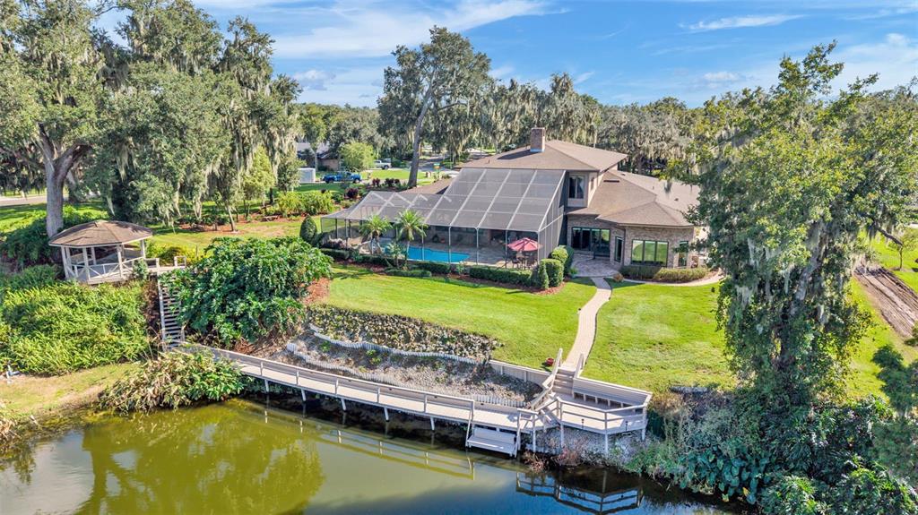 An aerial view of a house with a screened pool, gazebo, and wooden dock — 148 E CHRISTINA BOULEVARD, LAKELAND, FL