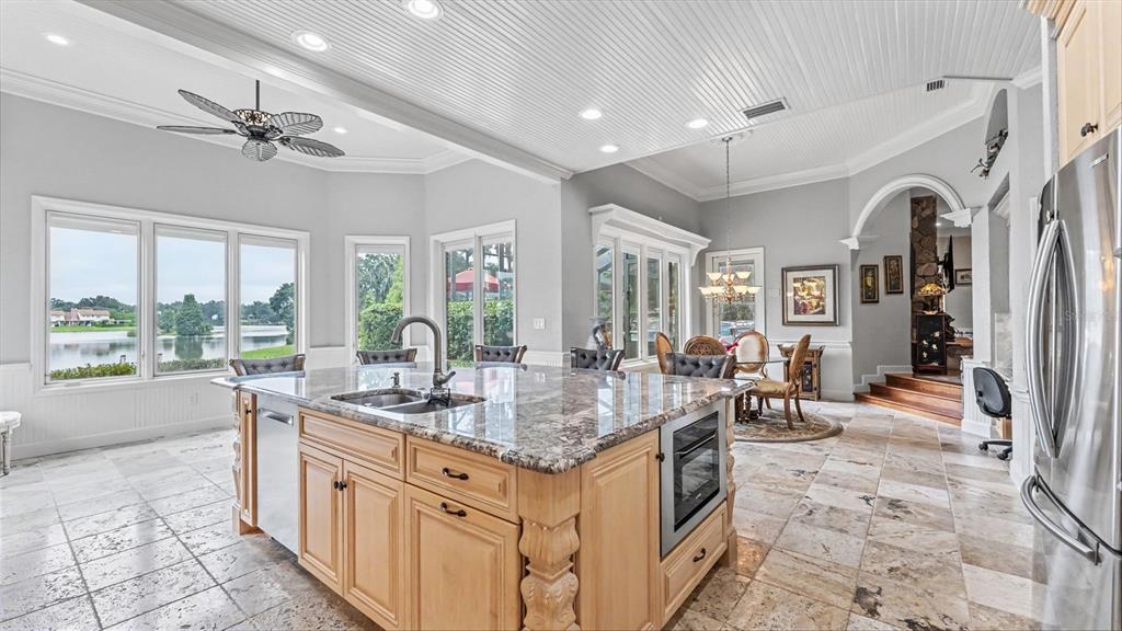 A kitchen with a large granite island, light wood cabinets, and views of a lake — 148 E CHRISTINA BOULEVARD, LAKELAND, FL