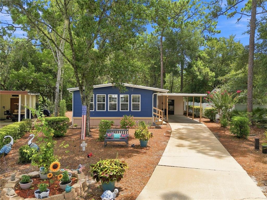 A blue mobile home with a concrete driveway and a landscaped front yard with trees — 552 PINE NEEDLE COURT, LAKE MARY, FL