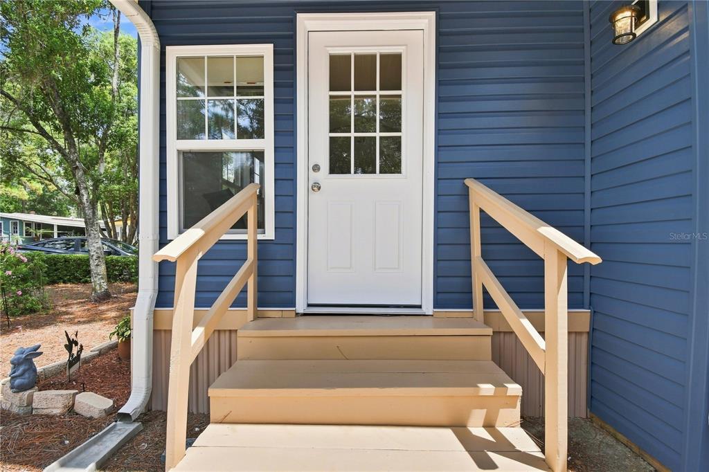 A white door with a window sits at the top of wooden stairs with railings — 552 PINE NEEDLE COURT, LAKE MARY, FL