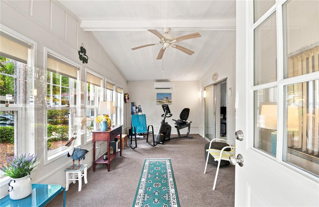 A sunroom features a ceiling fan, exercise equipment, a runner rug, and multiple windows — 552 PINE NEEDLE COURT, LAKE MARY, FL