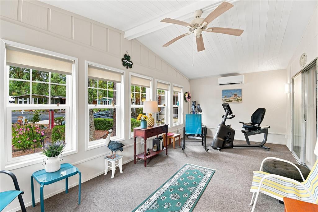A sunroom with carpeted floors, large windows, a ceiling fan, and exercise equipment — 552 PINE NEEDLE COURT, LAKE MARY, FL