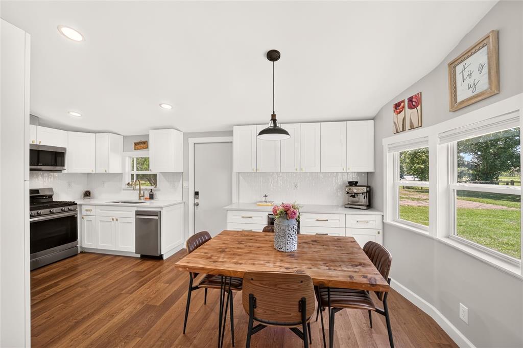 A kitchen with white cabinets, stainless steel appliances, a wooden table, and large windows — 8600 NE 41ST COURT, ANTHONY, FL