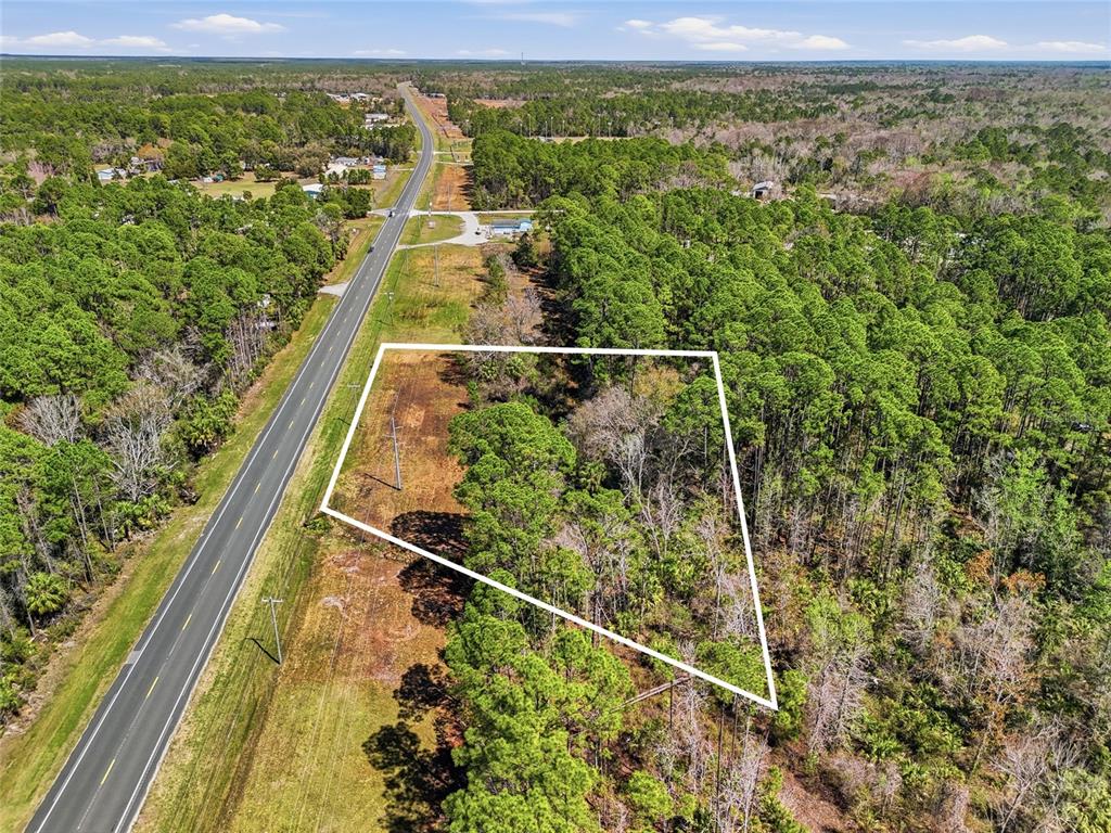 An aerial view shows a vacant, wooded lot outlined in white next to a highway — SW STATE ROAD 24, CEDAR KEY, FL
