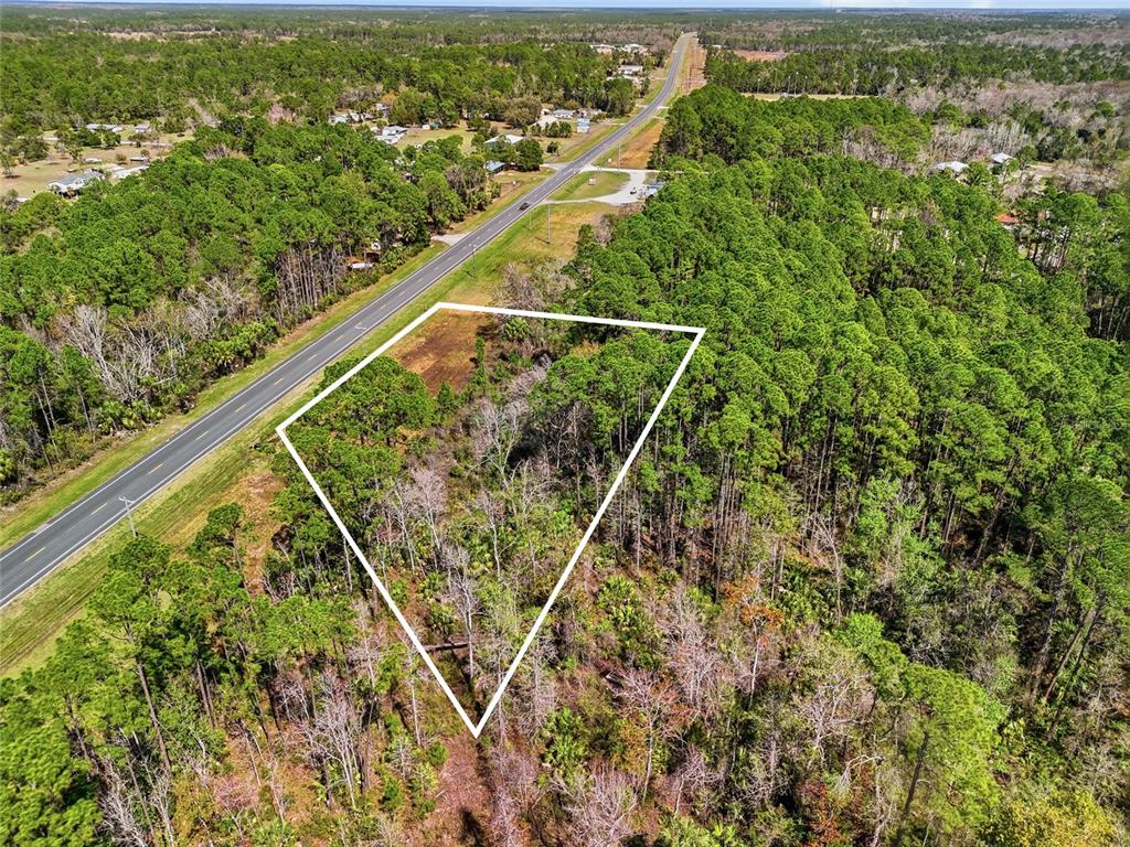 An aerial view shows a triangular plot of undeveloped land bordering a paved road — SW STATE ROAD 24, CEDAR KEY, FL