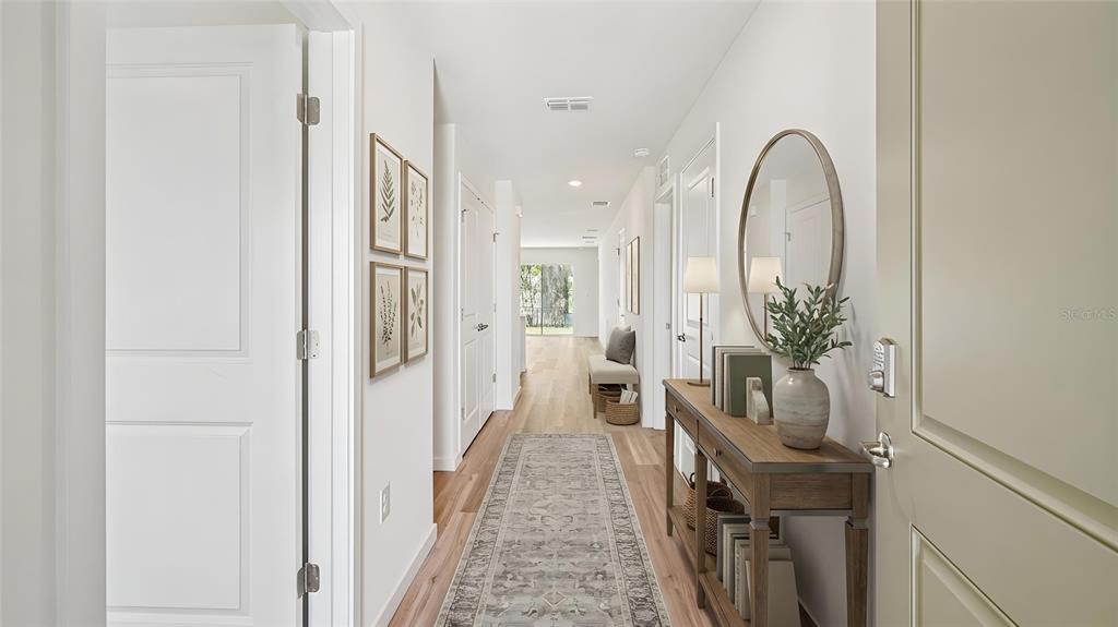 A bright hallway features light wood flooring, a runner rug, and a console table with decor — 4129 KONA CIRCLE, SPRING HILL, FL
