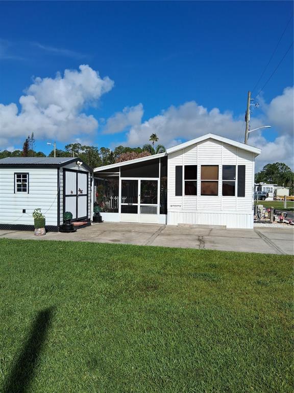 A white mobile home with a screened-in porch and a detached storage shed — 1359 SHIPWRECK LANE, ST CLOUD, FL