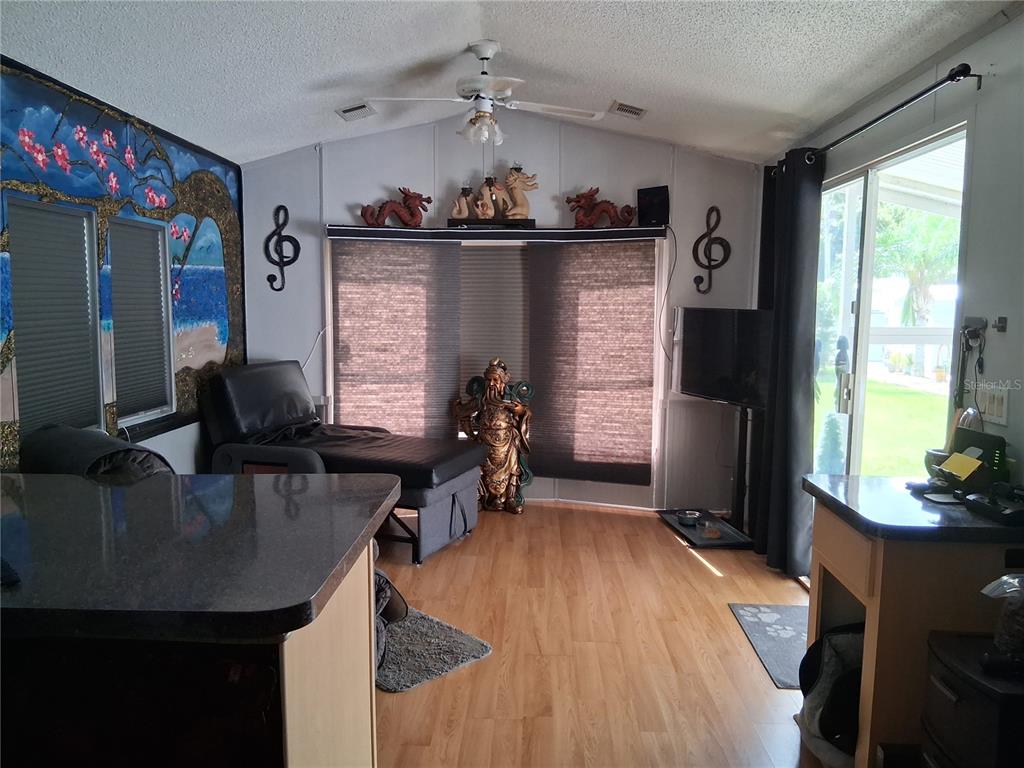 A living room with wood-look flooring, a ceiling fan, and Asian-inspired decor and furniture — 1359 SHIPWRECK LANE, ST CLOUD, FL