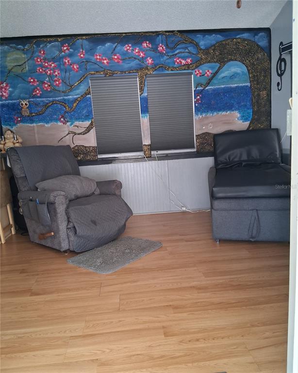 A room with wood-look flooring, two chairs, and a large mural of a tree on the wall — 1359 SHIPWRECK LANE, ST CLOUD, FL
