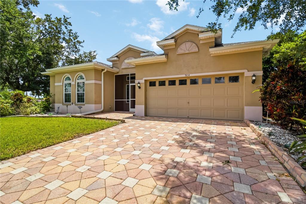 A tan single-story house with a paved driveway and a two-car garage — 5104 52ND AVENUE W, BRADENTON, FL