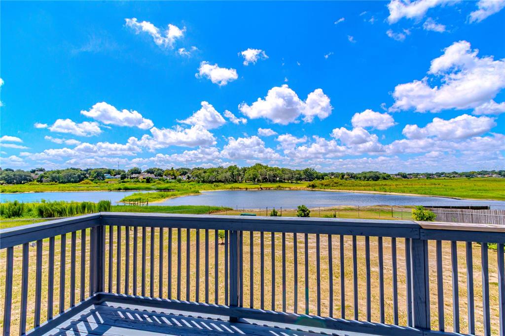 A wooden deck railing overlooks a pond and grassy landscape under a blue sky — 6526 LYNN ROAD, ORLANDO, FL