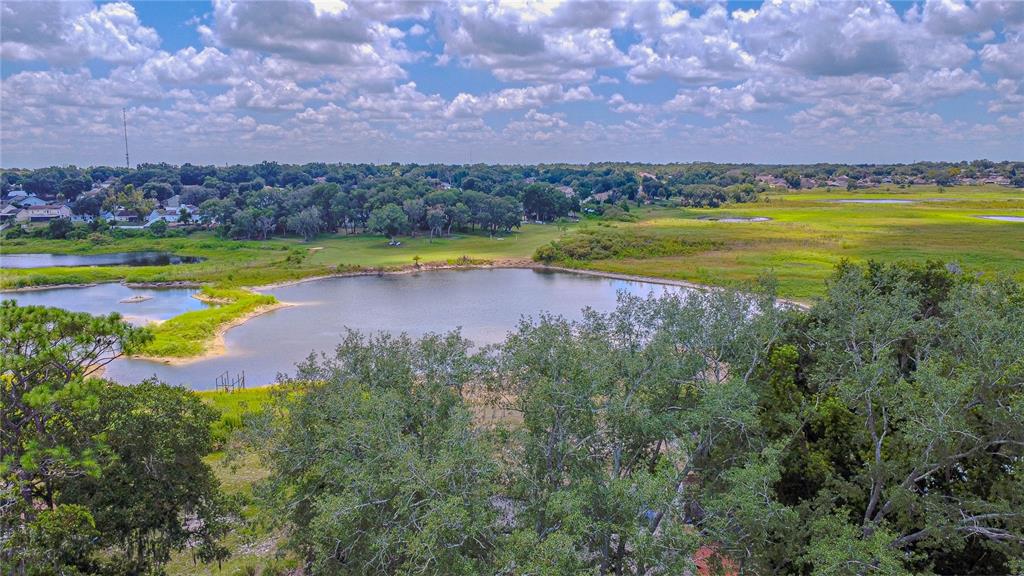 An aerial view shows a pond surrounded by trees and grassy fields under a cloudy sky — 6526 LYNN ROAD, ORLANDO, FL