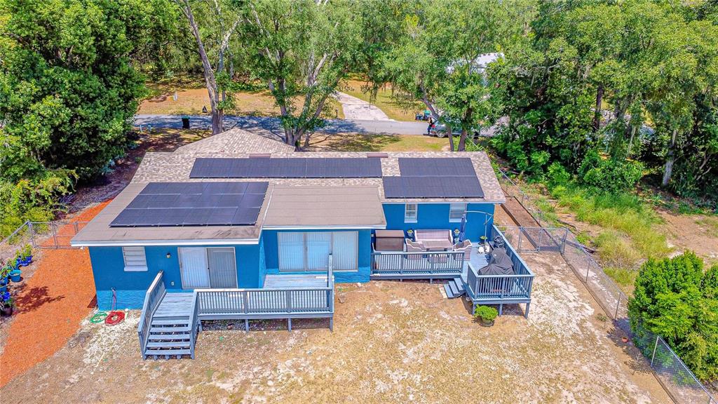 An aerial view of a blue house with solar panels on the roof and wooden decks — 6526 LYNN ROAD, ORLANDO, FL