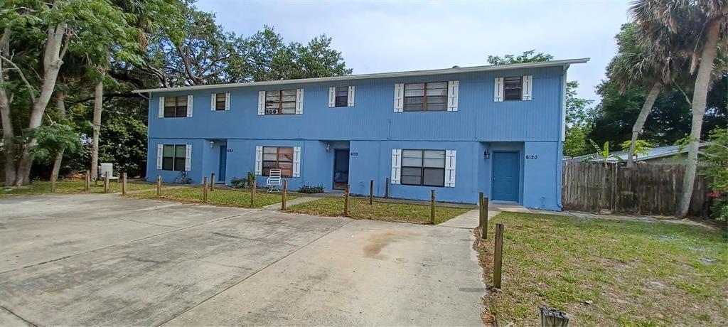 A two-story blue apartment building features a concrete parking area and a small front lawn — 6120 GEORGIA AVENUE, NEW PORT RICHEY, FL