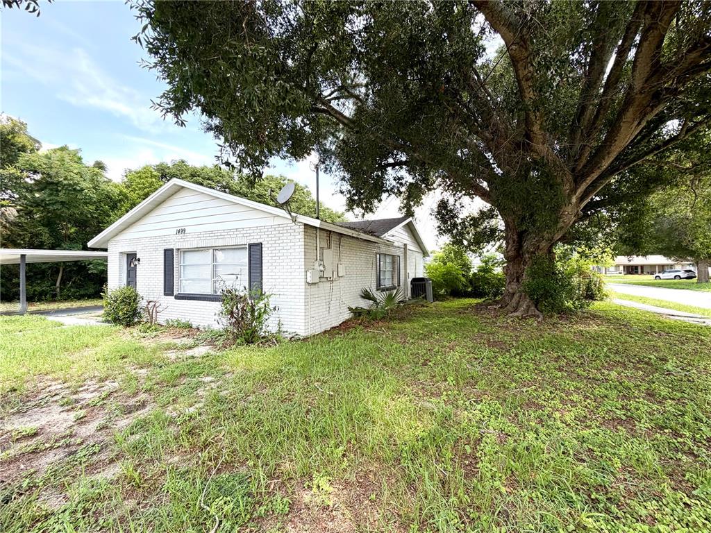 A white brick house with a large tree in the front yard — 1499 AVENUE E NE, WINTER HAVEN, FL