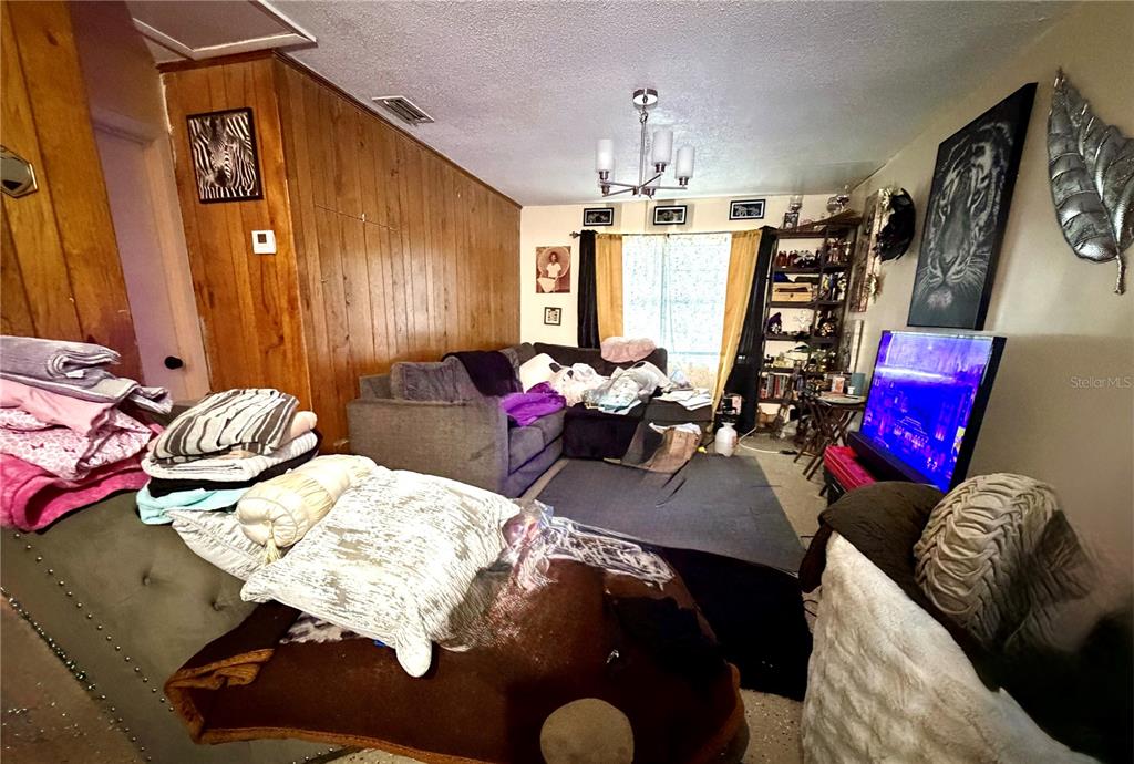 A living room features wood-paneled walls, a gray sectional sofa, and a television — 1499 AVENUE E NE, WINTER HAVEN, FL