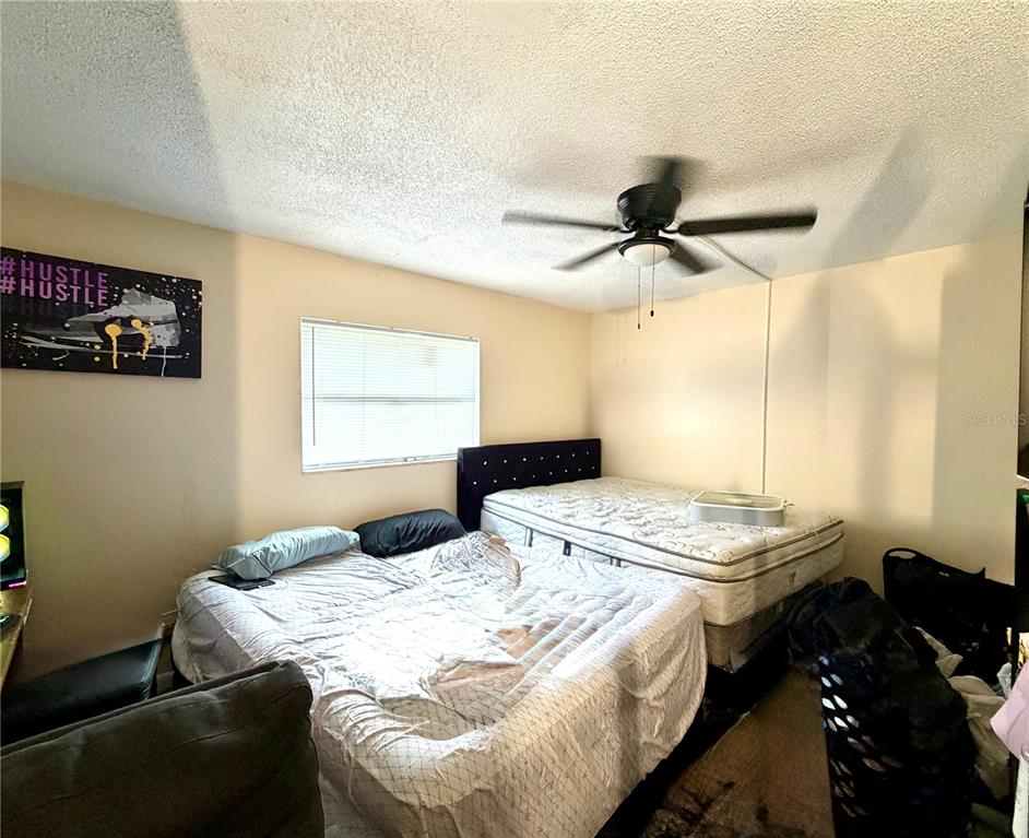 A bedroom features two beds, a ceiling fan, and a wall-mounted piece of art — 1499 AVENUE E NE, WINTER HAVEN, FL