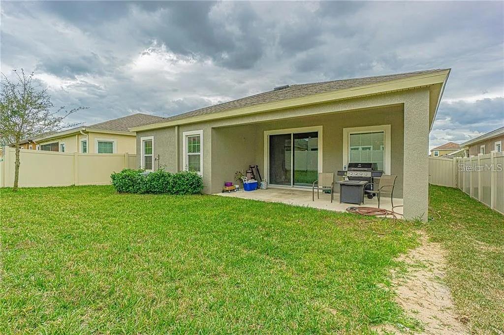 A backyard view of a house with a covered patio, sliding glass doors, and fencing — 843 VISCOUNT STREET, BRANDON, FL