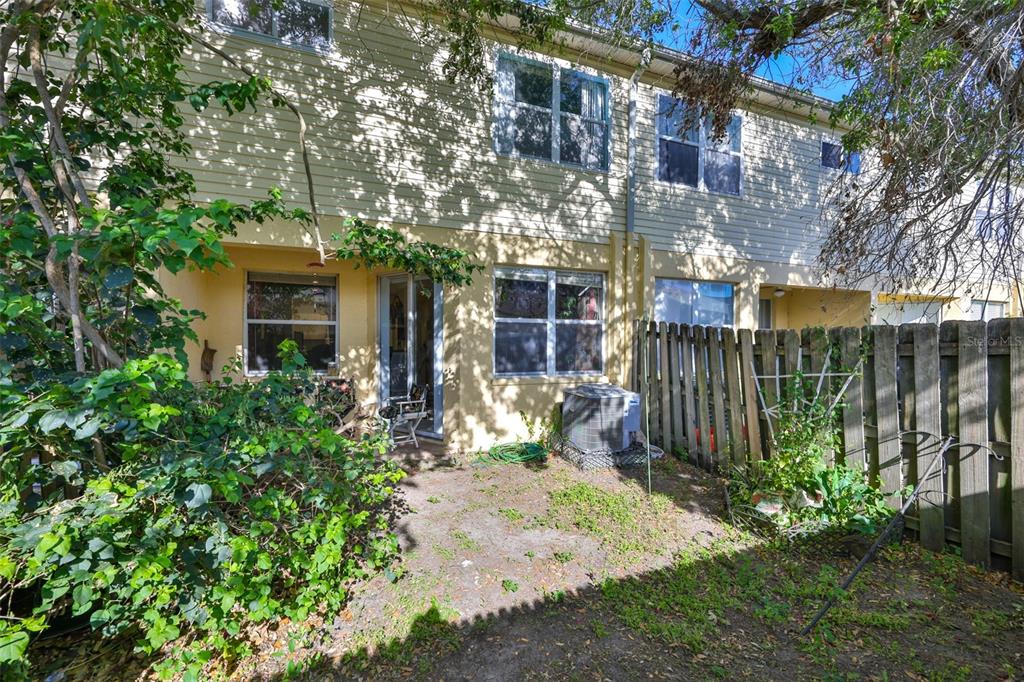 The exterior of a multi-unit townhouse complex features beige siding, white garage doors, and arched entryways — 6400 46TH AVENUE N UNIT 71, KENNETH CITY, FL