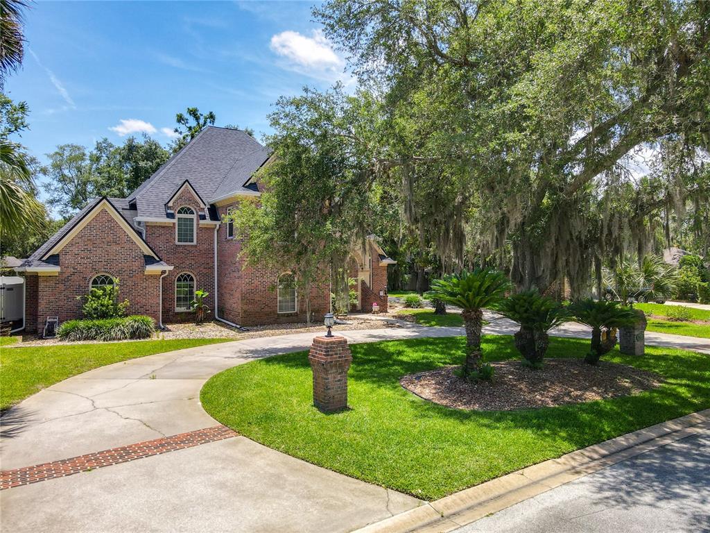 A two-story brick house with a curved concrete driveway and large moss-draped oak trees — 38 WINDING CREEK WAY, ORMOND BEACH, FL