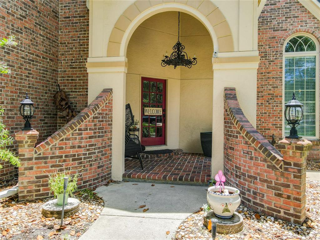 A brick home features an arched entryway with a red door and a hanging chandelier — 38 WINDING CREEK WAY, ORMOND BEACH, FL