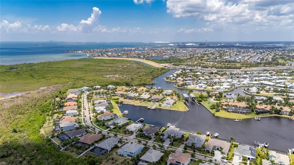 An aerial view shows a residential neighborhood with waterfront homes along canals near a coastline — 825 MANNS HARBOR DRIVE, APOLLO BEACH, FL